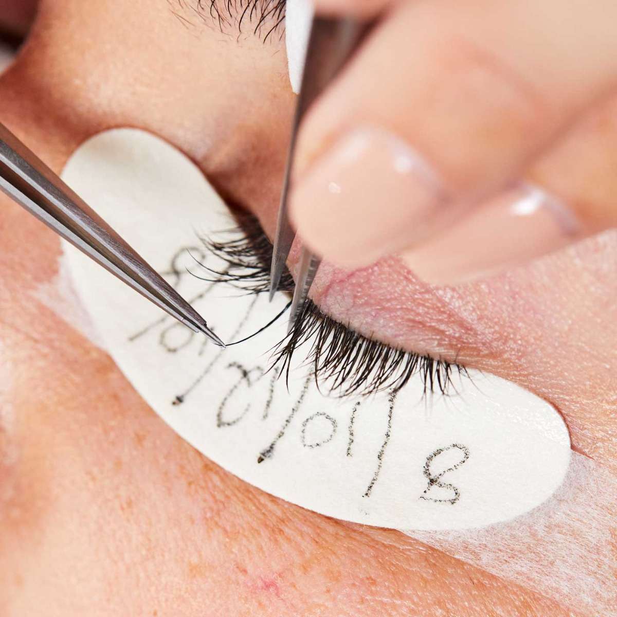 Close up image of lash extensions being applied during professional treatment